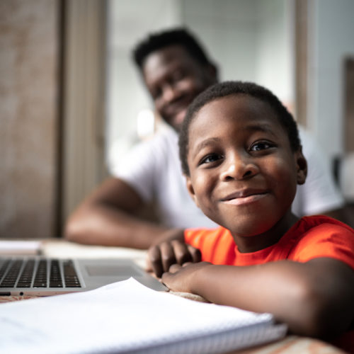 Portrait of father and son studying with laptop on a online class at home
