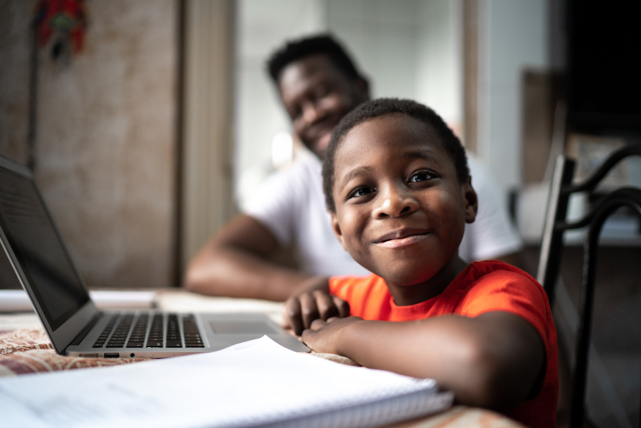 Portrait d'un père et de son fils étudiant avec un ordinateur portable sur un cours en ligne à la maison.